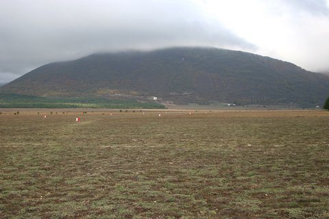 K_001 An oblique view down RWY 02 shows the hole this airfield is in - literally :). However, the surrounding hills and mountains give some excellent ridge lift